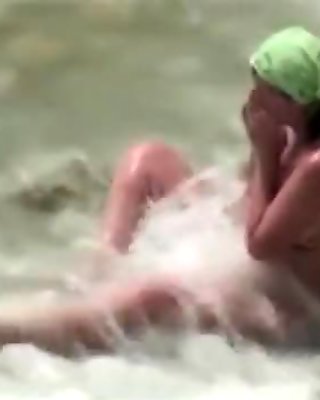 Voyeur tapes a milf jerking and sucking her man on a nude beach